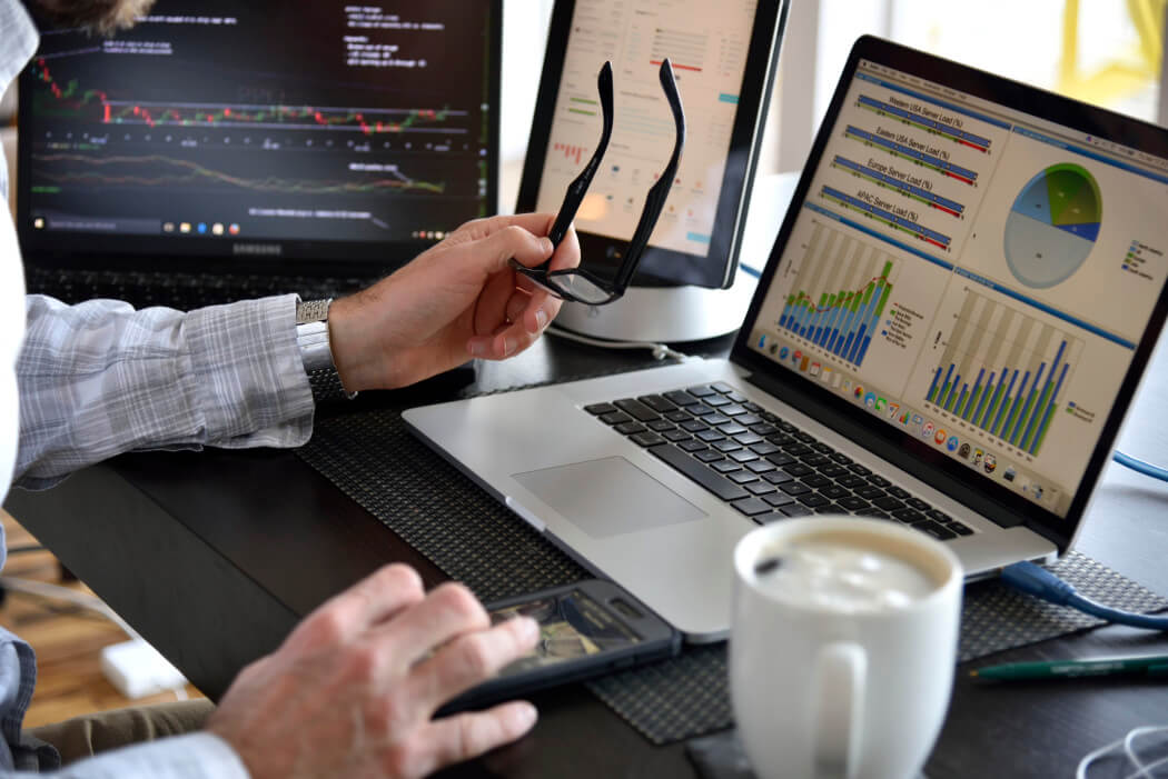 person-working-at-multi-computer-desk-with-many-screens-displaying-data-charts-and-graphs-information_t20_WQG0LY (1)
